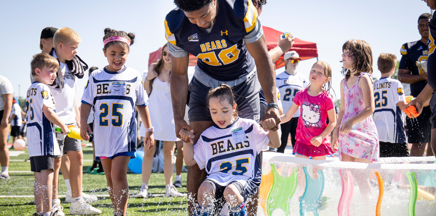 UNC football players posing with a young special needs kid wearing UNC football uniforms