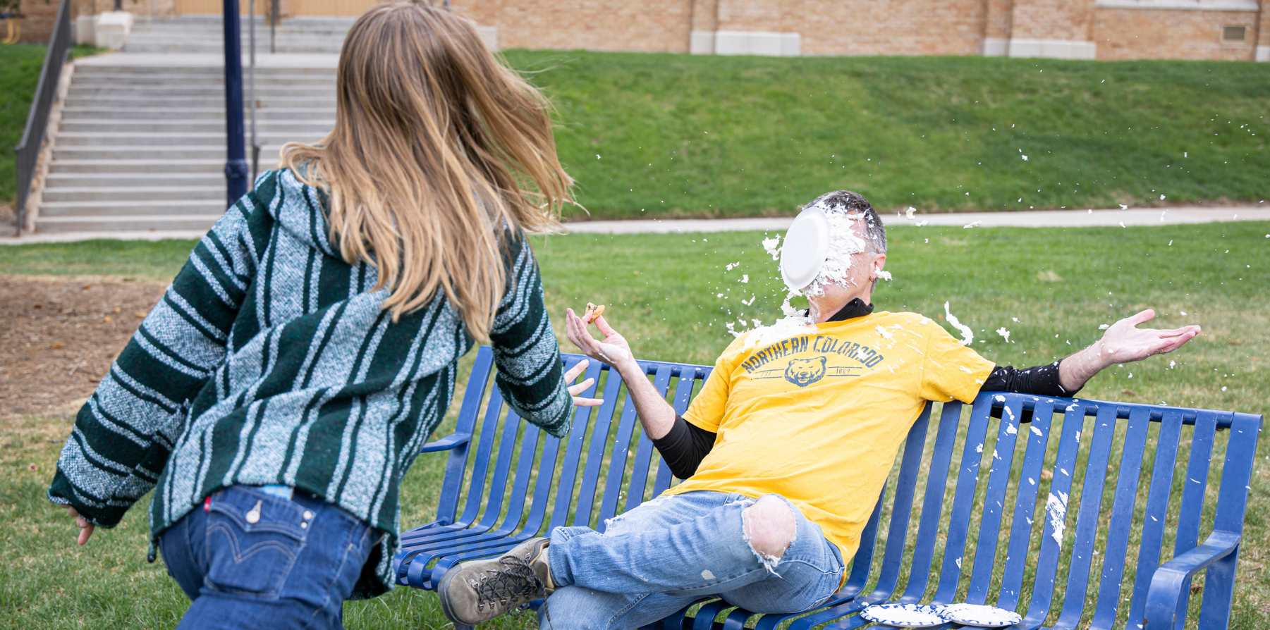 A student throwing a pie into the face of a professor during a fundraiser.