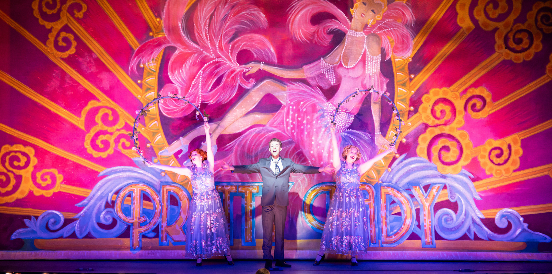 A student performer standing on stage in front of a colorful backdrop.
