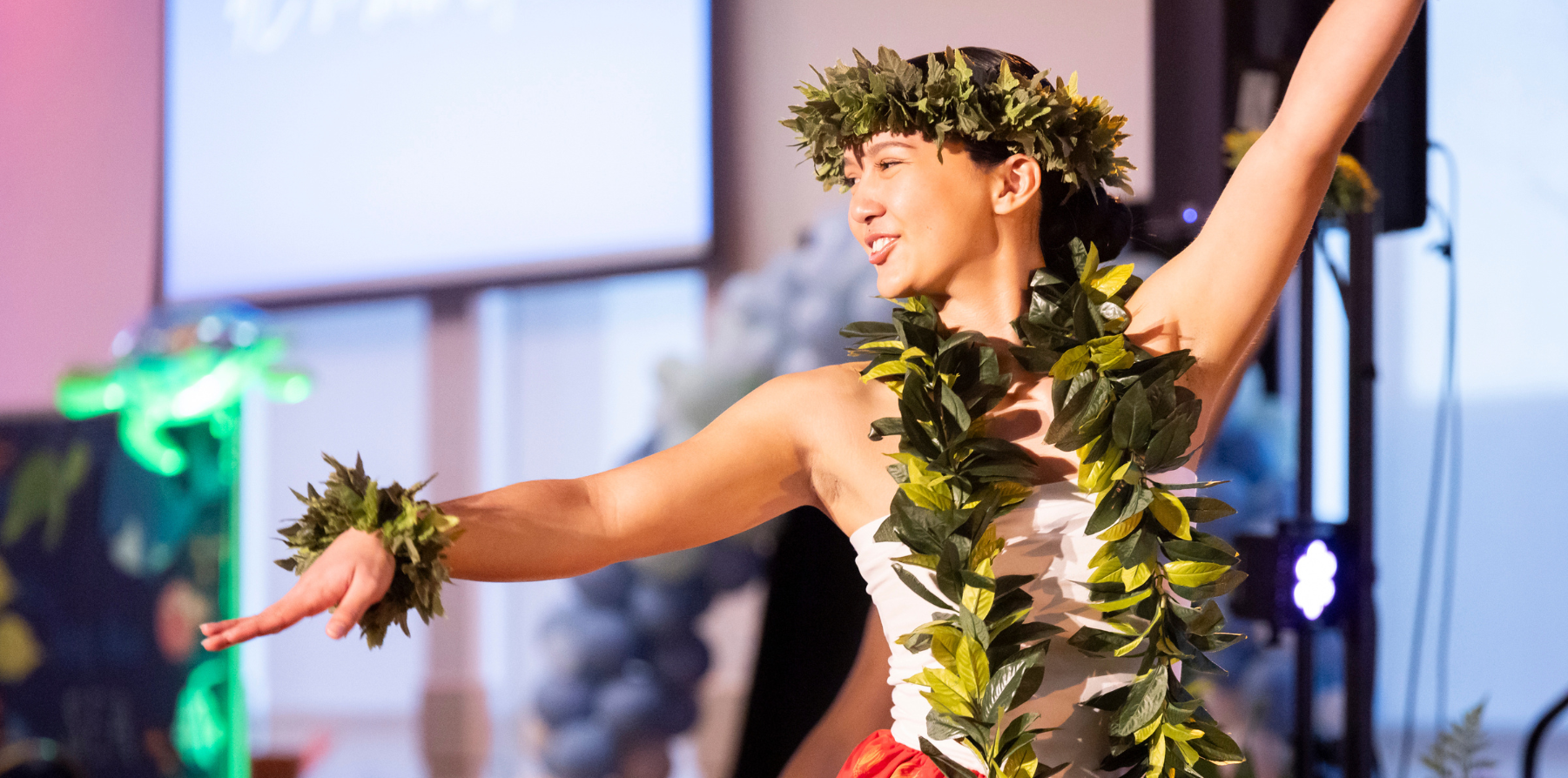 A student in cultural dress dancing on stage.