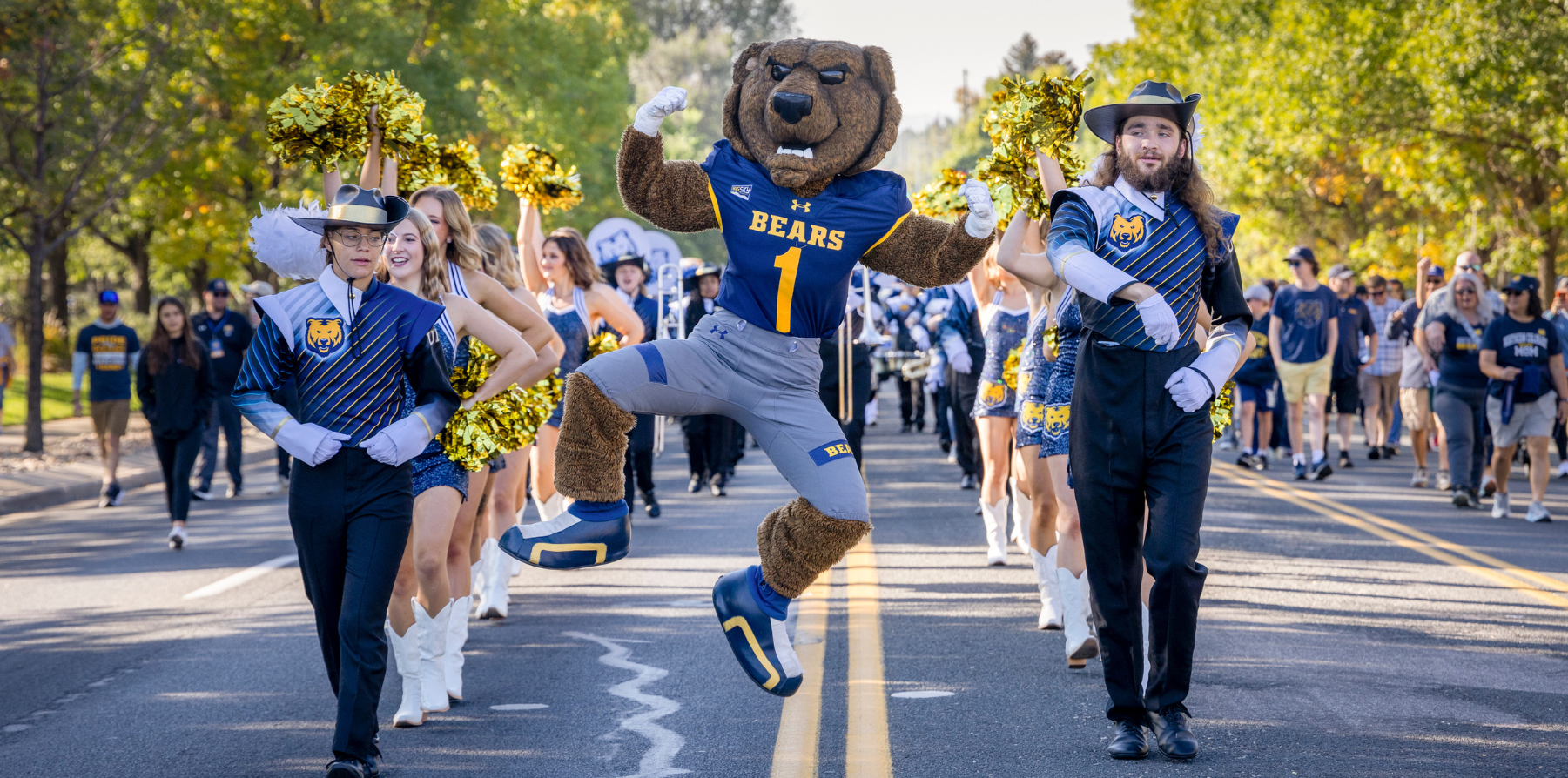 UNC's mascot, Klawz, marching in a parade alongside students in uniforms.