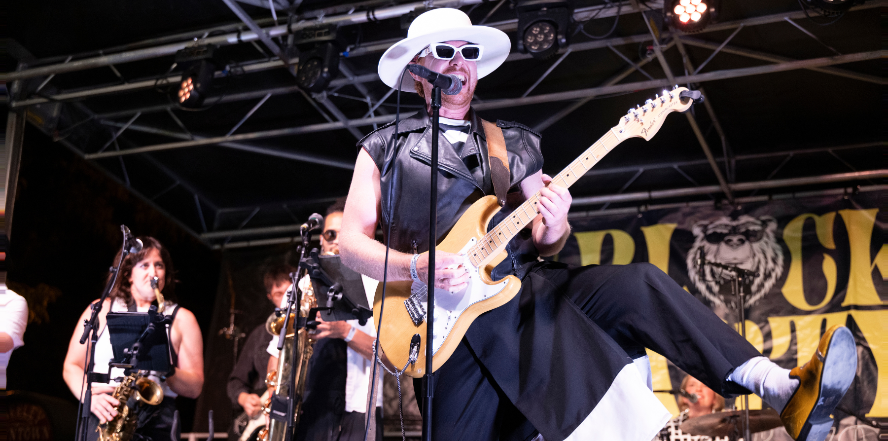A man in sunglasses playing guitar on a stage.
