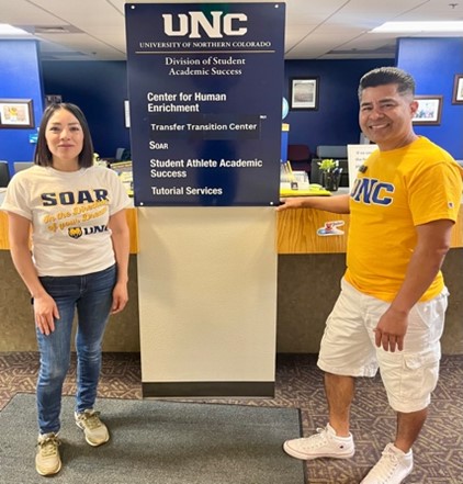 Dion Duran and student standing in front of UNC banner