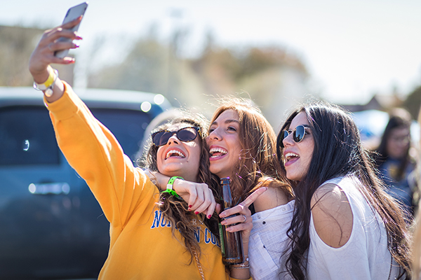 Girls holding a phone up taking a photo.