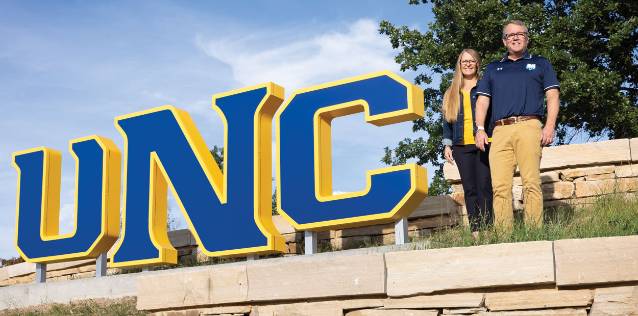 President Andy Feinstein and wife Kerry stand beside a new UNC sign during a Homecoming weekend
