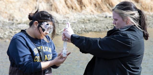 Professor and student water testing in river