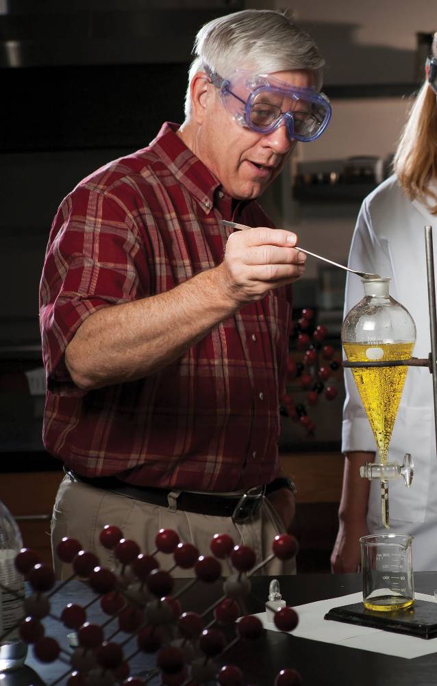James (Jim) Schreck in a chemistry lab wearing safety goggles using a dropper